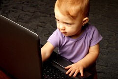 Cute baby pointing at lit laptop screen